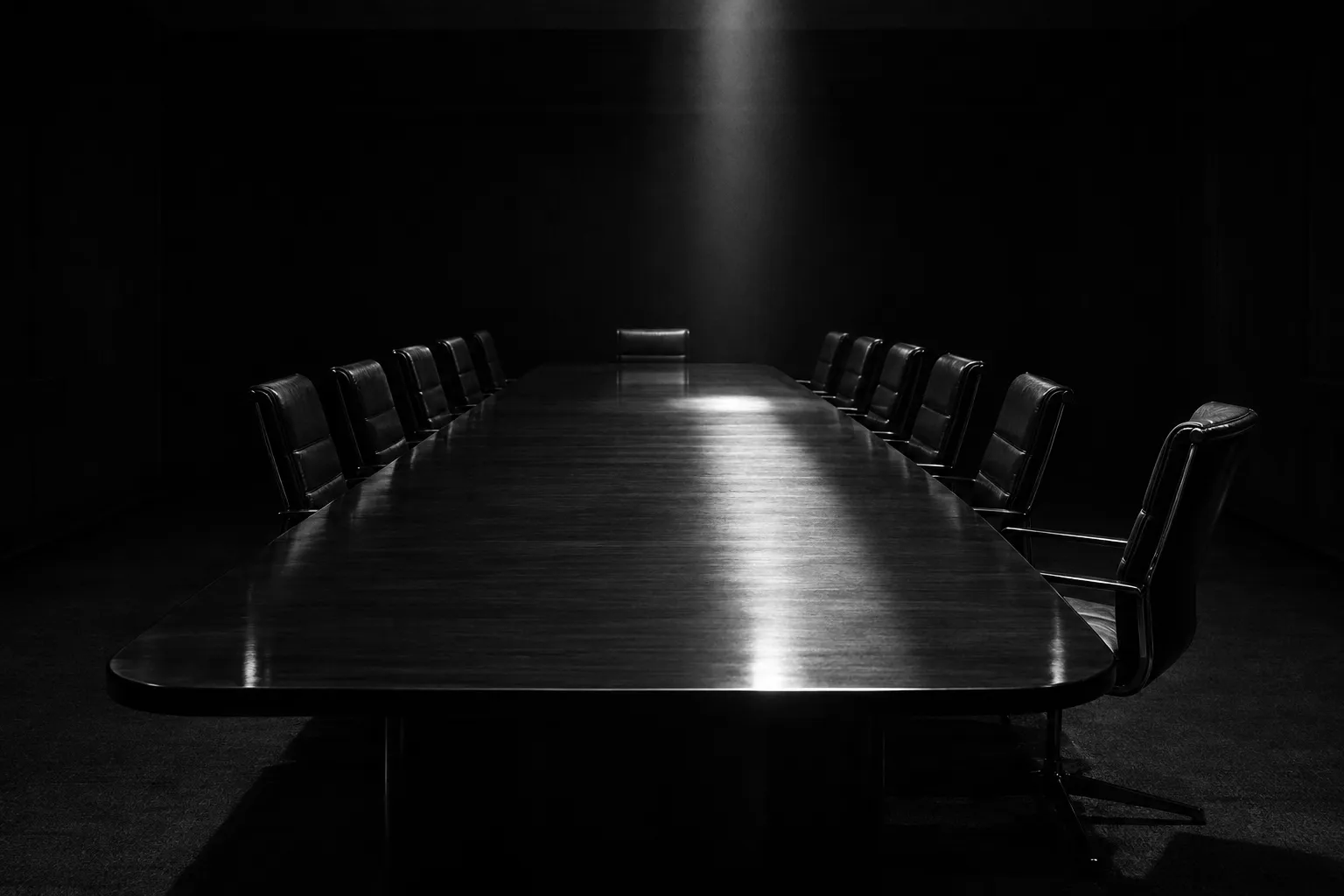 An empty boardroom table lit by a single beam of light